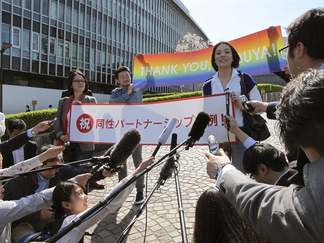 Koyuki Higashi, right, and her partner, Hiroko Masuhara, left, holding a banner reading: "Congratulations: the same sex partnership ordinance" speak to the media in front of Shibuya ward office in Tokyo Tuesday, March 31, 2015 after Shibuya ward became the first locale in Japan to recognize same sex partnerships as the "equivalent of a marriage," guaranteeing the identical rights of married couples with a landmark vote by the ward assembly. The couple, a rare visible and vocal lesbian couple in Japan, said they moved to Shibuya four months ago, just to apply for a same sex marriage certificate. They have been together for three years, and held a symbolic wedding at Tokyo DisneySea two years ago. Holding a rainbow banner reading "Thank You, Shibuya" is Fumino Sugiyama.