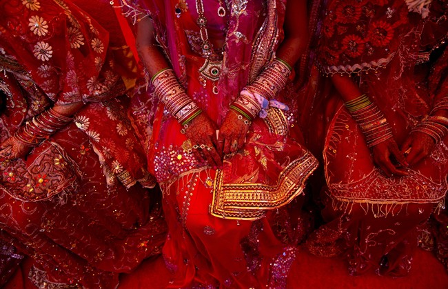 In this Feb. 20, 2015 file photo, Indian brides dressed in wedding finery wait for their grooms to arrive during a mass marriage ceremony in New Delhi, India.