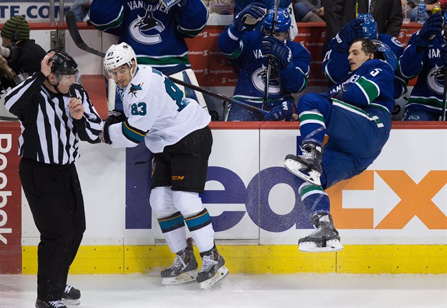San Jose Sharks' Matt Nieto (83) checks Vancouver Canucks' Luca Sbisa, of Switzerland, during the third period of an NHL hockey game in Vancouver, B.C., on Tuesday March 3, 2015.