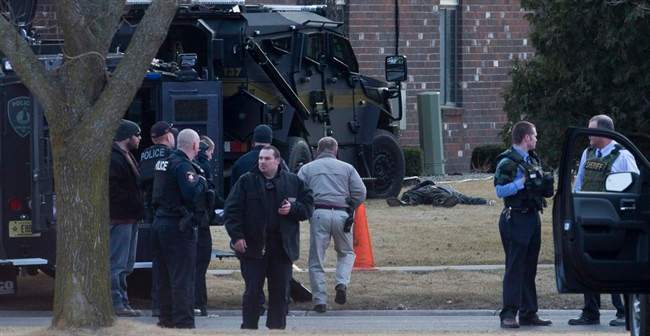 Law enforcement personnel gather near a body Tuesday, March 24, 2015, in Fond du Lac, Wis. Authorities say a Wisconsin state trooper was shot and killed in an exchange of gunfire with a person who matched the description of a bank robbery suspect. Police said the suspect also was killed. 