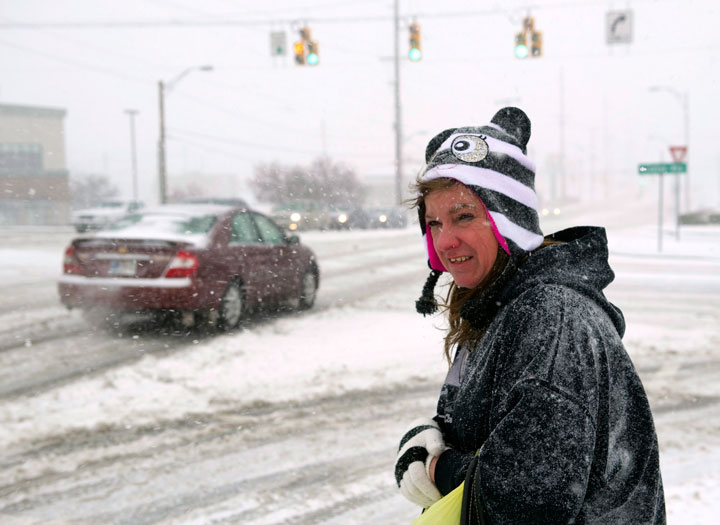 Diane Hancock, of Evansville, Ind., waits for a bus to take her home after work on Wednesday afternoon, March 4, 2015, in Evansville, Ind.  A winter storm was in its early stages and had dropped about an inch of snow in the area.