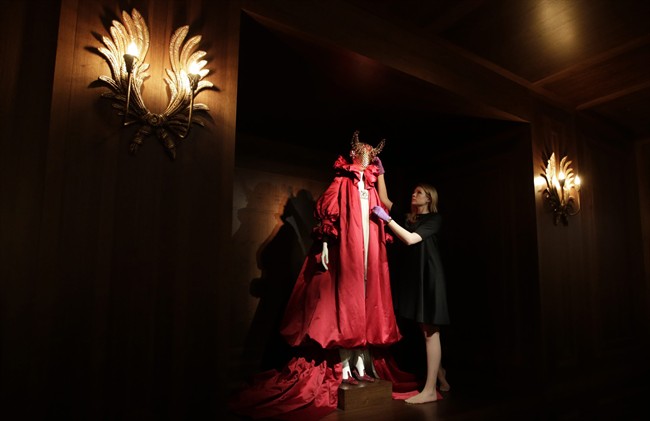 A member of the Victoria and Albert museum staff poses for photographers with a silk tulle dress from Alexander McQueen's 2008 Autumn Winter- 'The Girl Who Lived in a Tree ' show, during a media previw at the Alexander McQueen exhibition 'Savage Beauty' at the Victoria and Albert museum in London, Thursday, March, 12, 2015.