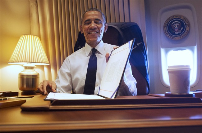 President Barack Obama smiles as he looks down at the legislation he just had signed awarding a Congressional Gold Medal to the people who participated in the “Bloody Sunday” march, Turnaround Tuesday, or the final Selma to Montgomery Voting Rights March in March of 1965, at his desk aboard Air Force One Saturday, March 7, 2015. The president was en route to Selma, Ala., to attend the 50th Anniversary of “Bloody Sunday,” which refers to the day in 1965 when police attacked marchers demonstrating for voting rights.