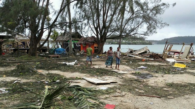 In this photo provided by China’s Xinhua News Agency, locals walk past debris in Port Vila, Vanuatu, after Cyclone Pam ripped through the tiny South Pacific archipelago, Sunday, March 15, 2015. Packing winds of 270 kilometers (168 miles) per hour, Cyclone Pam tore through Vanuatu early Saturday, leaving a trail of destruction.