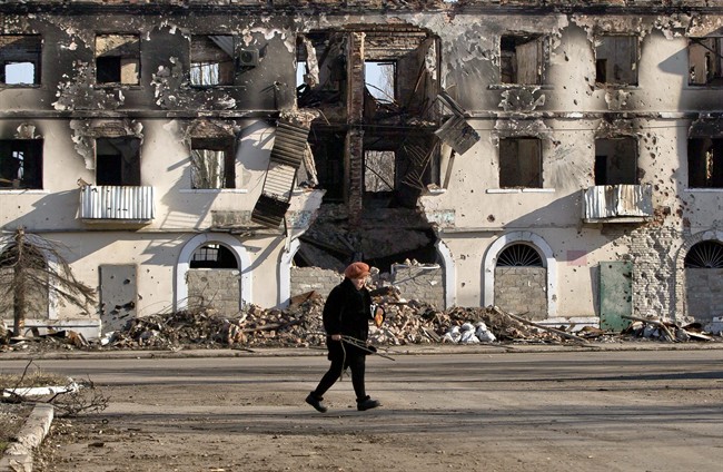 An elderly woman walks by a destroyed building in Vuhlehirsk, Ukraine, Monday, March 9, 2015. 