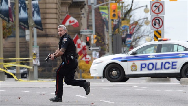 An Ottawa police officer runs with his weapon drawn in Ottawa on Wednesday, Oct. 22, 2014.