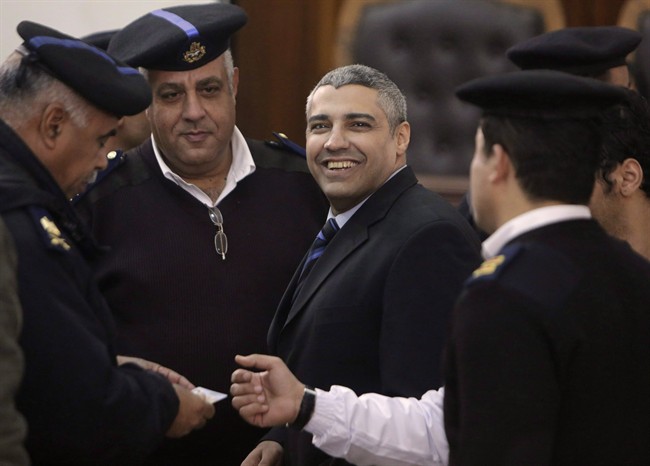 Canadian Al-Jazeera English journalist Mohamed Fahmy speaks with Egyptian policemen during his retrial in Cairo, Egypt, Monday, Feb. 23, 2015. 