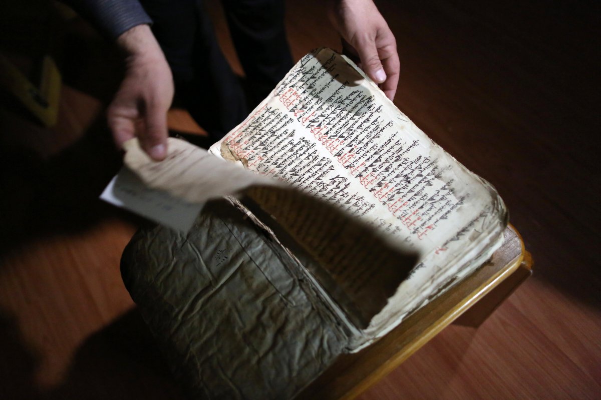 Raad Abdul-Ahed, 45, who was displaced from his home by the advance of Islamic State militants, shows a centuries-old handwritten biblical manuscript in the old Syriac language.