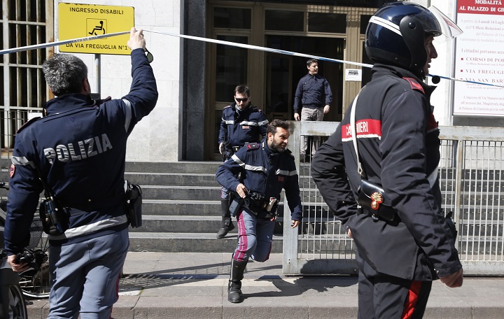 Policemen run out of the tribunal building in Milan, Italy, after a shooting was reported inside a courtroom Thursday, April 9, 2015. 
