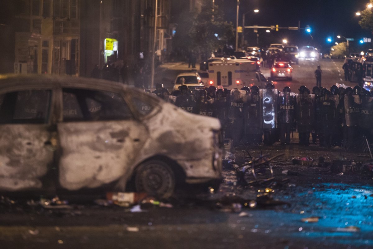 Police retreat from the hulks of burned out cars in the middle of an intersection during riots in Baltimore, USA on April 27, 2015. Protests following the death of Freddie Gray from injuries suffered while in police custody have turned violent with people throwing debris at police and media and burning cars and businesses.