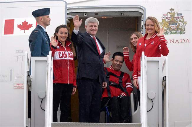 Prime Minister Stephen Harper, centre, accompanied by Canadian Pan Am and Parapan Am athletes waves as he departs for Panama to participate in the Summit of the Americas, in Ottawa on Friday, April 10, 2015.