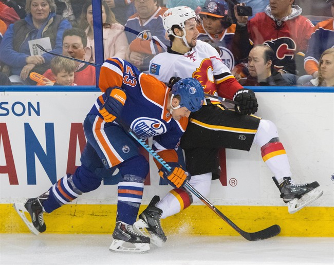 Calgary Flames' Josh Jooris (86) gets hit by Edmonton Oilers' Matt Hendricks during third period NHL hockey action in Edmonton, Alta., on Saturday April 4, 2015. The Flames won 4-0.