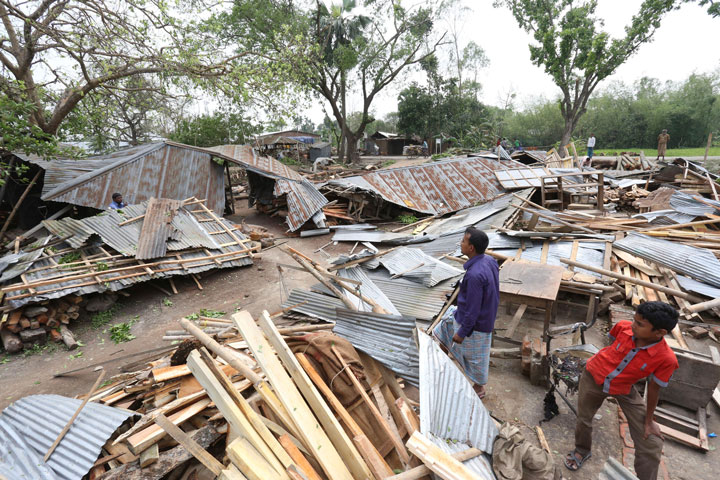 In this Sunday, April 5, 2015 photo, Bangladeshi villagers inspect the scene after tropical storms damaged houses in Gabtoli area, in northern Bogra district, Bangladesh. 