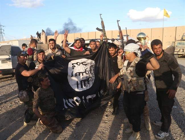 Iraqi security forces and allied Shiite militiamen celebrate as they hold a flag of the Islamic State group they captured in Tikrit.