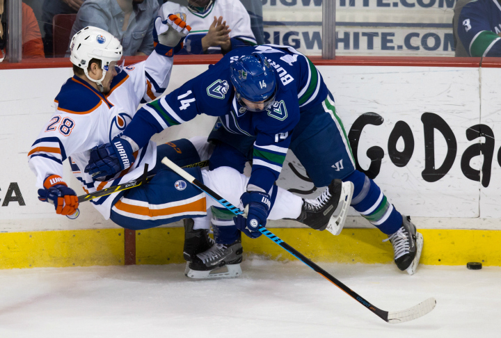 Vancouver Canucks' Alex Burrows, right, checks Edmonton Oilers' Matt Fraser during the third period of an NHL hockey game in Vancouver, B.C., on Saturday April 11, 2015. 
