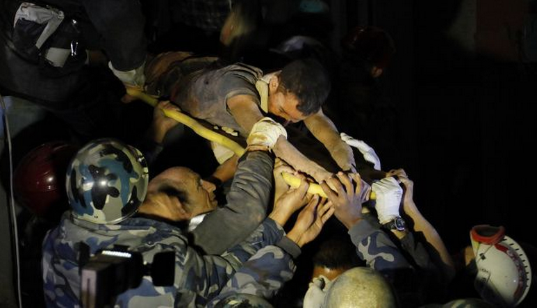 Survivor Rishi Khanal, 27, is freed by French rescuers from the ruins of a three-story hotel in the Gangabu area of Kathmandu, Nepal, Tuesday, April 28, 2015. 