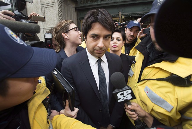 Jian Ghomeshi is escorted by police out of court past members of the media in Toronto on Wednesday, November 26, 2014.