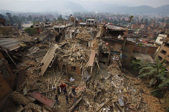 Rescue workers remove debris as they search for victims of earthquake in Bhaktapur near Kathmandu, Nepal, Sunday, April 26, 2015. A strong magnitude earthquake shook Nepal's capital and the densely populated Kathmandu Valley before noon Saturday, causing extensive damage with toppled walls and collapsed buildings, officials said. (AP Photo/Niranjan Shrestha).