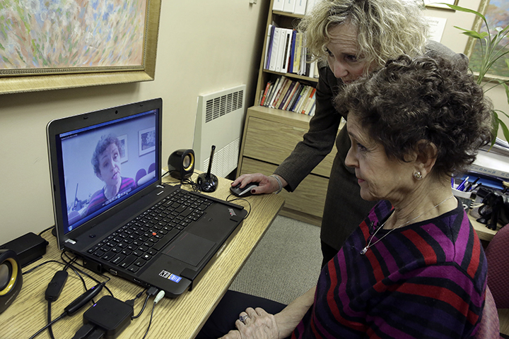 Tamara Rusoff-Hoen, right, watches a video she recorded for her mother, Louise Irving, with Charlotte Dell, Director of Social Services at The Hebrew Home of Riverdale, in New York, Wednesday, March 25, 2015. 