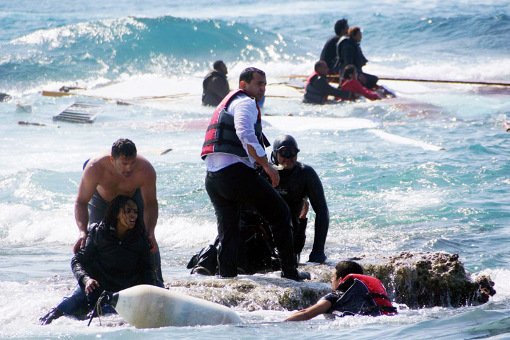 Local residents and rescue workers help a woman after a boat carrying migrants sank off the island of Rhodes, southeastern Greece, on April 20, 2015. 