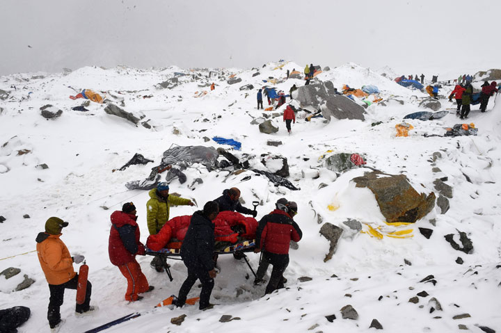 In this photograph taken on April 25, 2015, rescuers use a makeshift stretcher to carry an injured person after an avalanche triggered by an earthquake flattened parts of Everest Base Camp.  