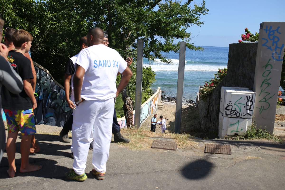 Rescuers and onlookers stand on April 12, 2015 near the beach in Les Aigrettes, on the western coast of the French Indian Ocean island of La Reunion, after a 13-year-old boy was attacked and killed by a shark. 