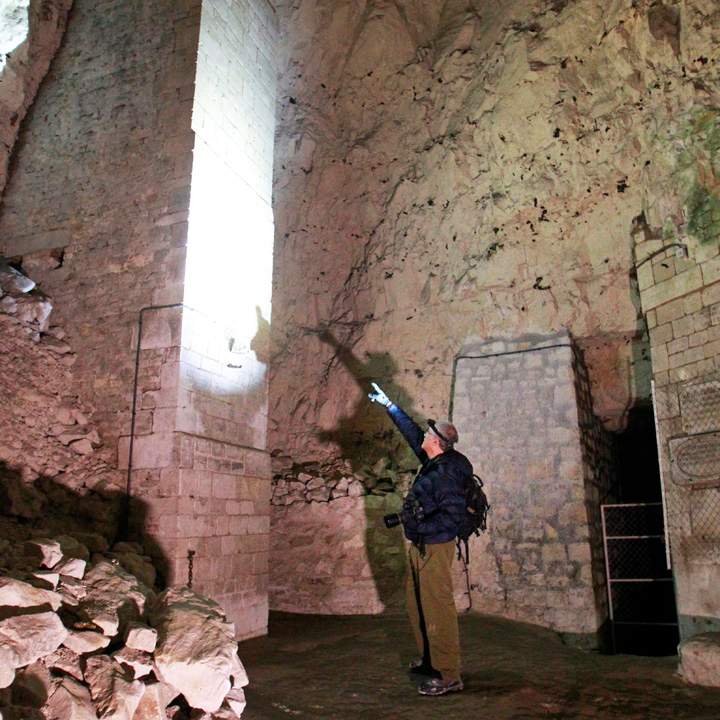 Jeffrey Gusky, a photographer and physician from Texas points at graffiti in a former chalk quarry, at the Cite Souterraine