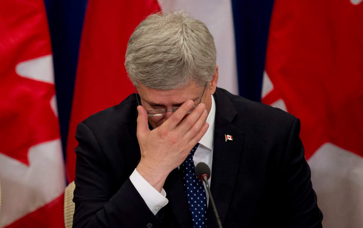 Prime Minister Stephen Harper adjusts his glasses as he waits for a meeting with business leaders to begin Thursday May 30, 2013 on Parliament Hill in Ottawa. THE CANADIAN PRESS/Adrian Wyld