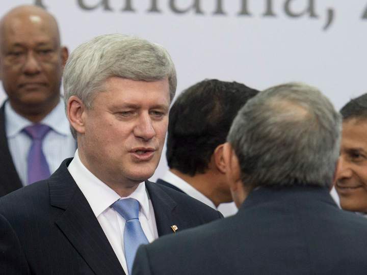 Canadian Prime Minister Stephen Harper speaks briefly with Cuban President Raul Castro as leaders take their places for the official family photo at the Summit of the Americas in Panama City, Panama Saturday April 11, 2015.