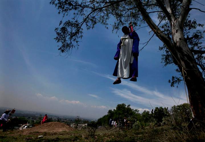A parishioner playing the role of Judas, one of the 12 original apostles of Jesus Christ, who is known for his kiss and betrayal of Jesus in exchange for money, hangs (suspended with a safety belt) from a tree, as part of a Good Friday custom of Santa Cruz, Mexico, Friday, April 3, 2015.