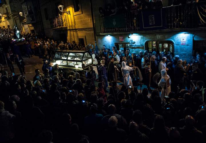 Devotees look at a masked penitent from La Santa Vera Cruz brotherhood who beats himself while taking part in an Easter procession known as ‘Los Picaos’ in the small village of San Vicente de La Sonsierra, northern Spain, Friday, April 3, 2015.