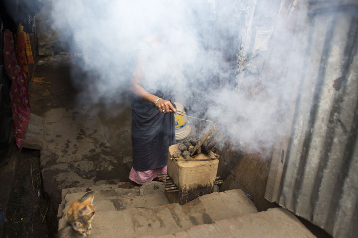 In this Tuesday, March 31, 2015 photo, smoke emits as an Indian woman prepares a makeshift stove for cooking food at her home on the outskirts of Gauhati, India.