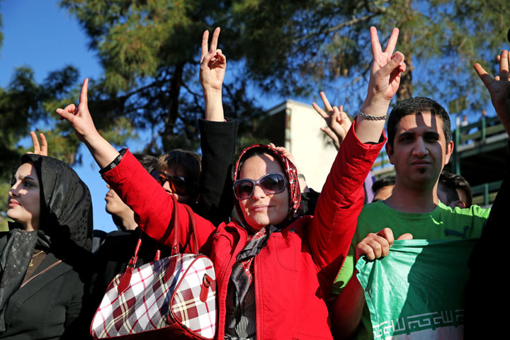 Iranians flash the victory sign while waiting for arrival of Foreign Minister Mohammad Javad Zarif from Lausanne, Switzerland, at the Mehrabad airport in Tehran, Iran, Friday, April 3, 2015.