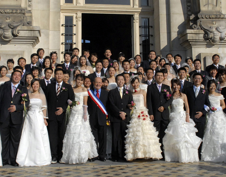 In this photo dated Oct. 2008, Tours mayor, Jean Germain, center, wearing a sash in the colors of the French flag, poses with a group of recently married Chinese couples in front of the city hall in Tours, France.