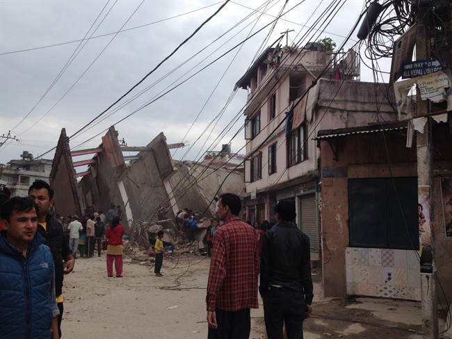 People walk next to ruble after an earthquake in Kathmandu, Nepal, Saturday, April 25, 2015. 