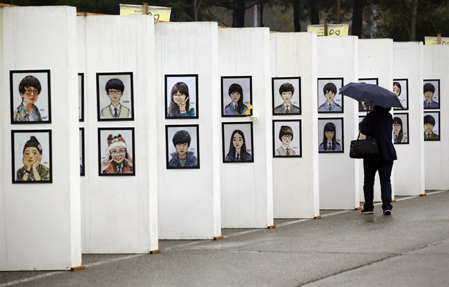 A woman looks at caricatures of the victims of the sunken ferry Sewol outside a group memorial altar in Ansan, South Korea, Thursday, April 16, 2015. Tears and grief mixed with raw anger Thursday as black-clad relatives mourned the 300 people, mostly high school kids, killed one year ago when the ferry Sewol sank in cold waters off the southwestern South Korean coast. (AP Photo/Lee Jin-man).