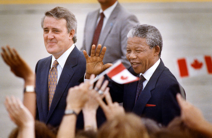 Nelson Mandela greets people as he walks with Prime Minister Brian Mulroney on his arrival in Ottawa, Ontario on June 17, 1990. 