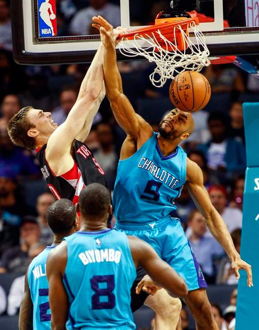 Toronto Raptors forward Tyler Hansbrough, left, dunks over Charlotte Hornets forward Gerald Henderson in the first half of an NBA basketball game Wednesday, April 8, 2015 in Charlotte, N.C. 
