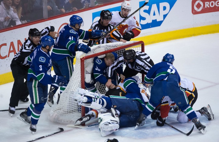 Vancouver Canucks goalie Eddie Lack, of Sweden, tangles with Calgary Flames' Brandon Bollig during the second period of game 2 of an NHL Western Conference first round playoff hockey series in Vancouver, B.C., on Friday April 17, 2015. 