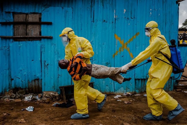 This Sept. 5, 2014, photo by New York Times photographer Daniel Berehulak, part of a winning series, shows James Dorbor, 8, suspected of being infected with Ebola, being carried by medical staff to an Ebola treatment center in Monrovia, Liberia. 