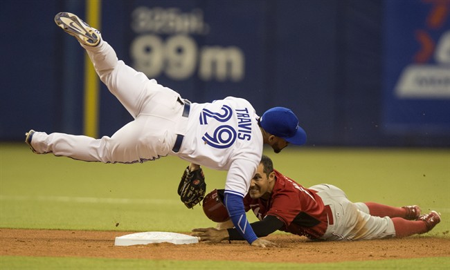 Toronto Blue Jays' Devon Travis falls over Cincinnati Reds' Ben Klimesh after throwing to first to complete the double play during sixth inning MLB exhibition action Friday, April 3, 2015 in Montreal.