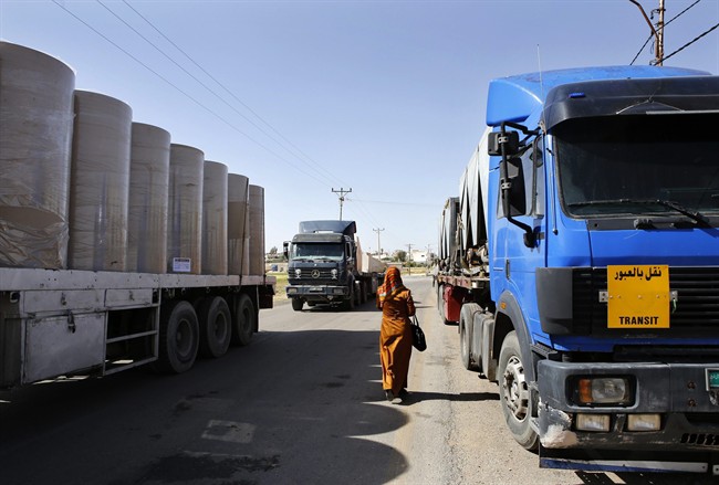 In this picture taken on Sunday, April 26, 2015, a woman walks through lines of trailer trucks sitting idle at the Jaber border crossing between Jordan and Syria north of Mafraq.