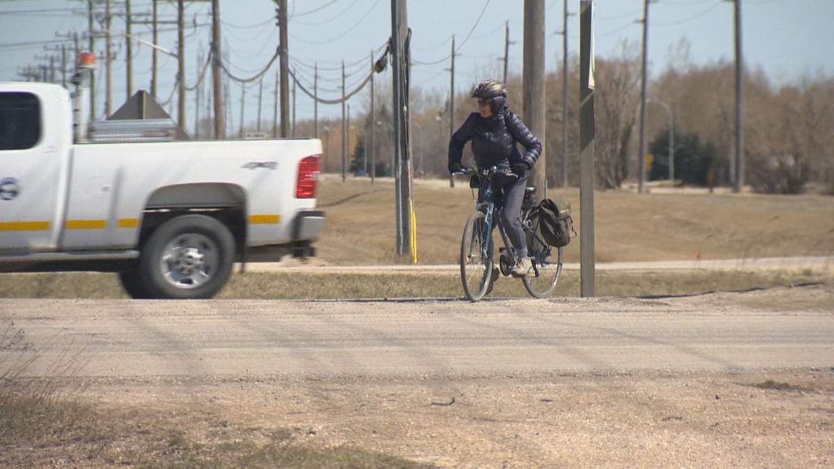 A cyclist crosses the busy North Perimeter Highway at Raleigh Street.