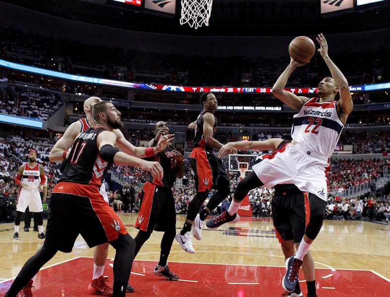 Washington Wizards forward Otto Porter Jr. (22) shoots as Toronto Raptors center Jonas Valanciunas (17), forward Patrick Patterson (54), and guard DeMar DeRozan (10) defend during the first half of Game 3 in the first round of the NBA basketball playoffs Friday, April 24, 2015, in Washington. The Wizards won 106-99. 