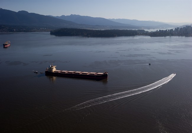 Crews on spill response boats work around the bulk carrier cargo ship Marathassa after a bunker fuel spill on Burrard Inlet in Vancouver, B.C., on Thursday April 9, 2015. The federal coast guard is defending its response to an oil spill in Vancouver's harbour amid questions about how the slick washed up on beaches to the north. THE CANADIAN PRESS/Darryl Dyck.