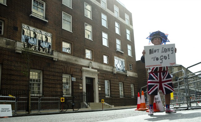 Terry Hutt poses for the media with a sign that reads 'Not Long to Go' as he waits with other royal fans for Kate, the Duchess of Cambridge to go into the Lindo wing at St Mary's Hospital to give birth to her second child in London, Friday, April 24, 2015.