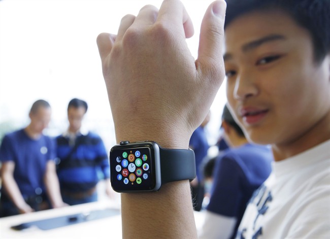 A customer tries on an Apple Watch at an Apple Store in Hong Kong Friday, April 10, 2015. From Beijing to Paris to San Francisco, the Apple Watch made its debut Friday. Customers were invited to try them on in stores and order them online.