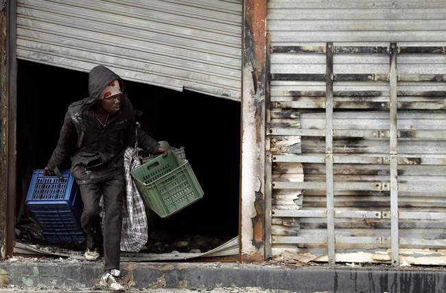 A man leaves a burnt shop owned by a foreign national in Johannesburg, South Africa, Sunday, April 19, 2015.