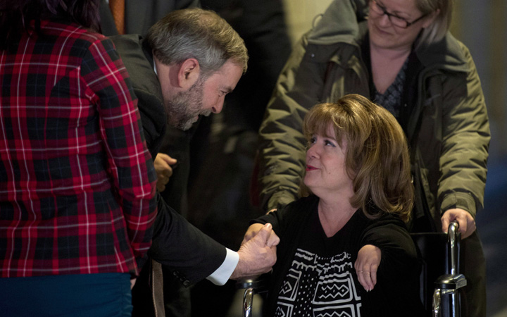 NDP leader Tom Mulcair stops to speak with Mercedes Benegbi who is a thalidomide survivor and executive director of the Thalidomide Victims Association of Canada in the foyer of the House of Commons Monday January 26, 2015 in Ottawa. 