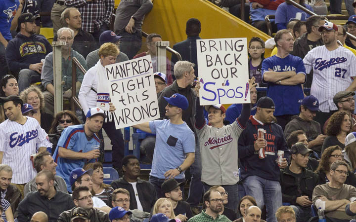 Fans hold up signs as the Toronto Blue Jays face the Cincinnati Reds in Grapefruit League play on April 3, 2015 in Montreal. 